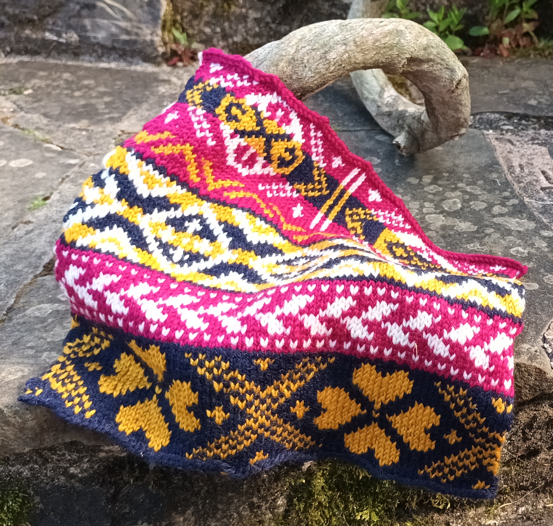 Pink, navy, white and gold Fairisle knitted sample draped over stone