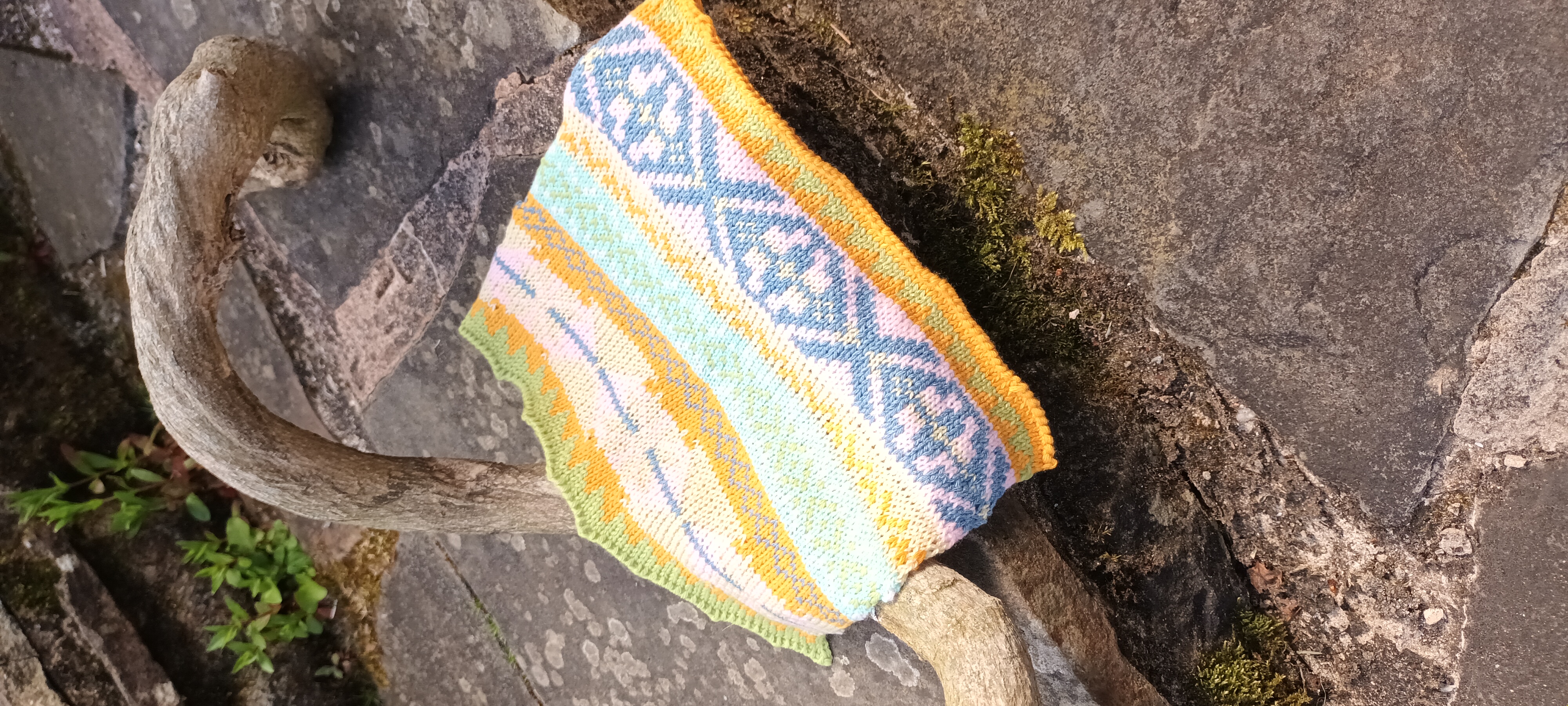 Pastel Fairisle knitted sample draped over curved wood