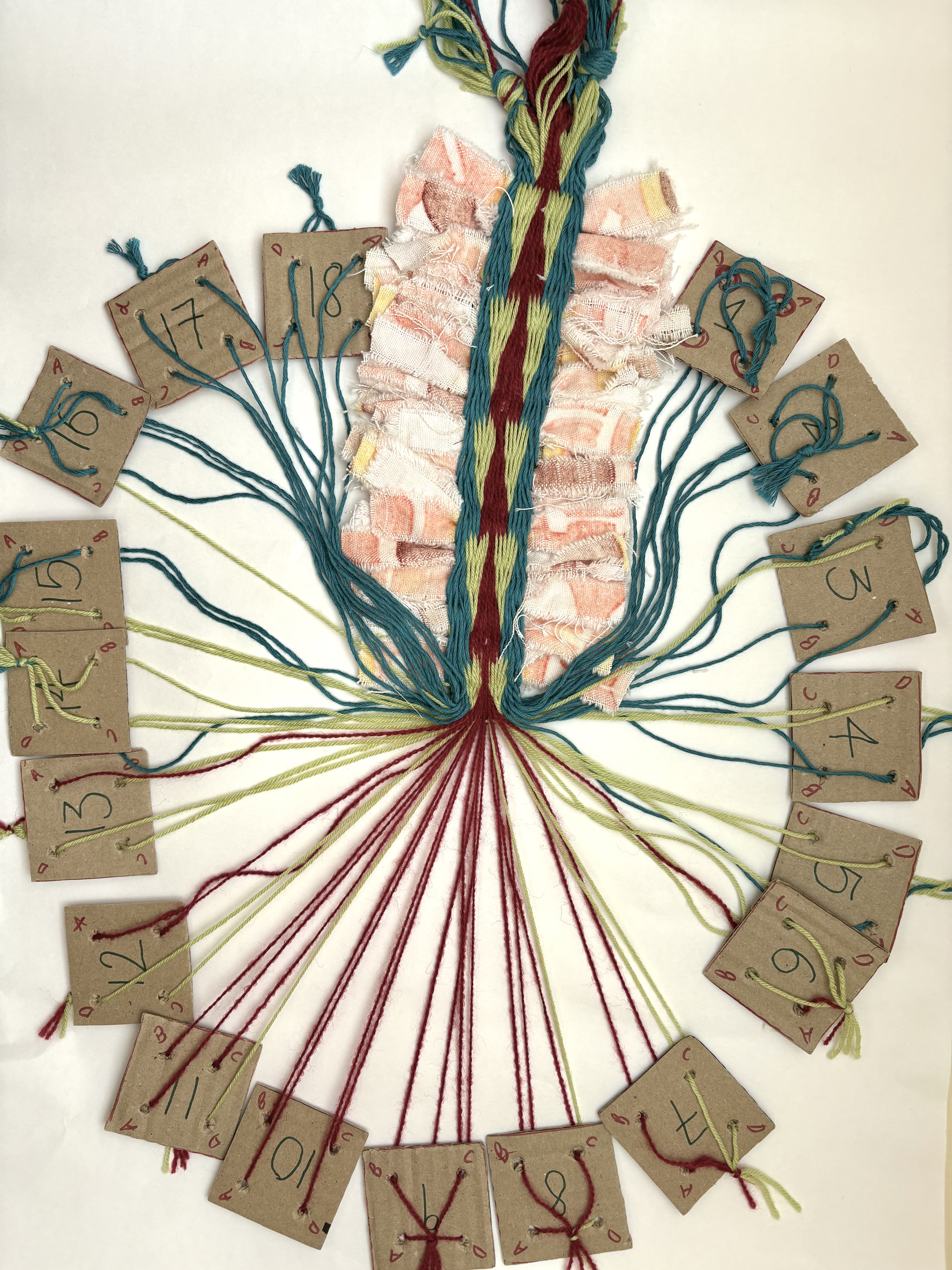 Card weaving work in progress with numbered cards, coloured threads and fabric texture samples